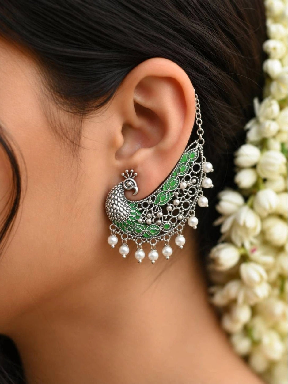 Peacock ear cuff worn on a woman's ear with jasmine flowers in hair showing full drape and pearl drop fringe