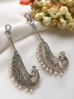 Pair of oxidised silver peacock ear cuff earrings with green enamel and pearl drops on white fabric