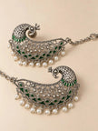 Close-up flat lay of two peacock ear cuff earrings showing intricate silver texture and pearl drop fringe