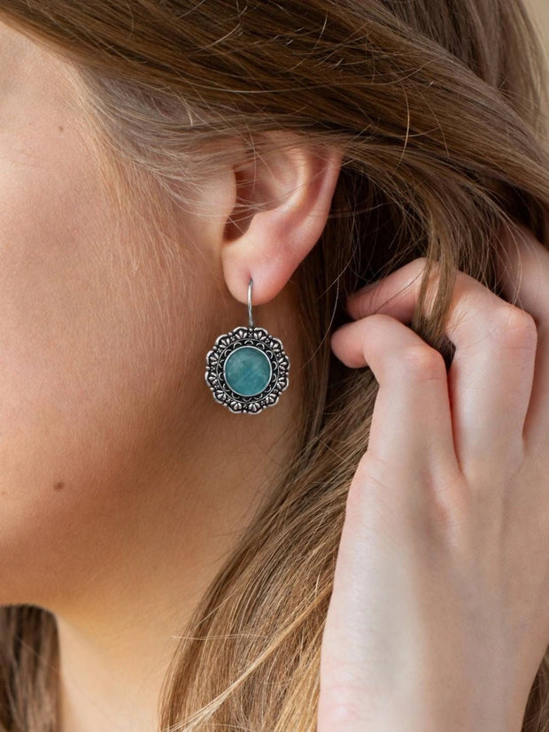 Oxidised silver turquoise floral drop earring worn on a woman's ear showing scale and drape