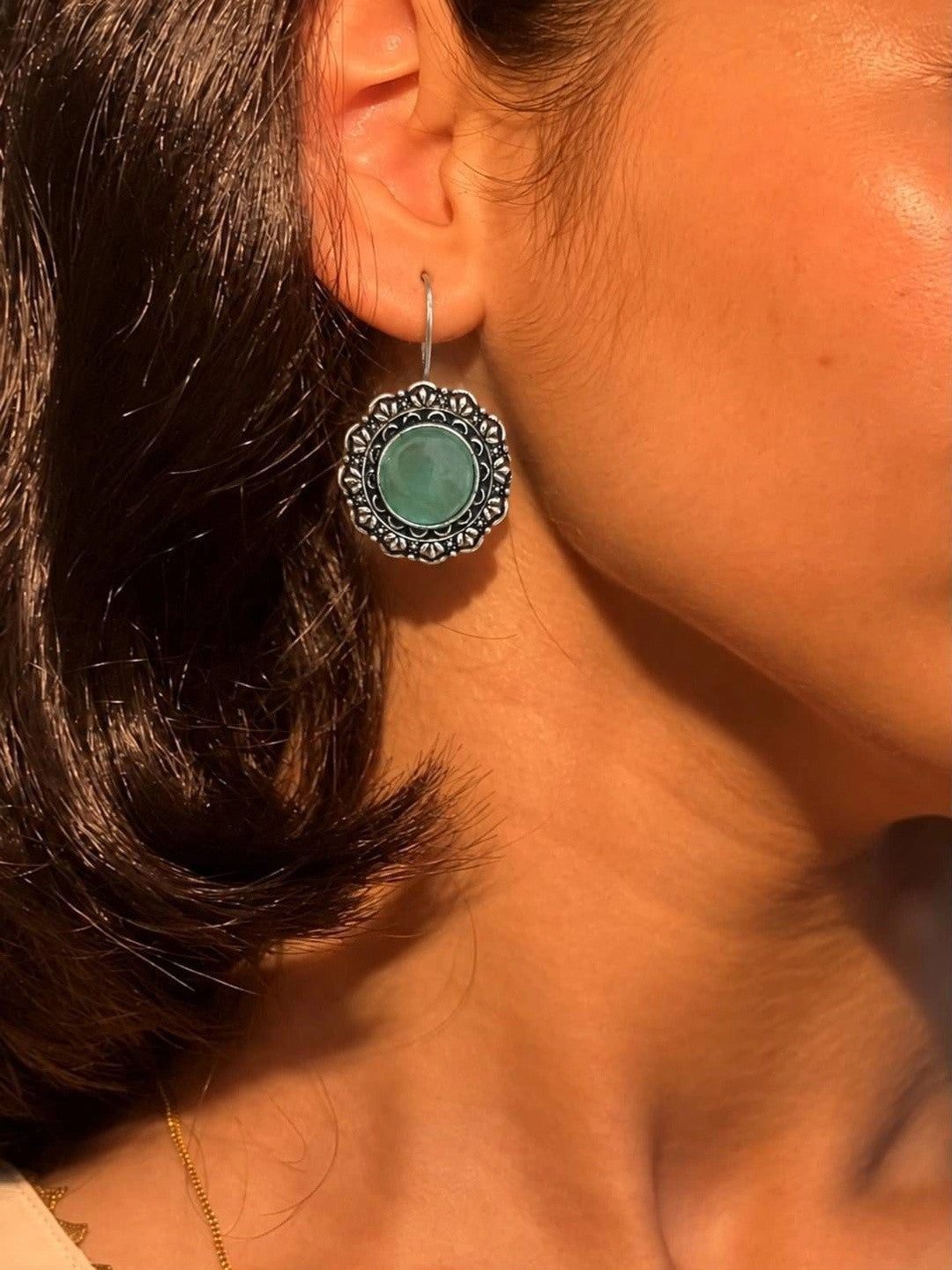 Oxidised silver floral circular earring worn on a woman's ear showing scale and fit