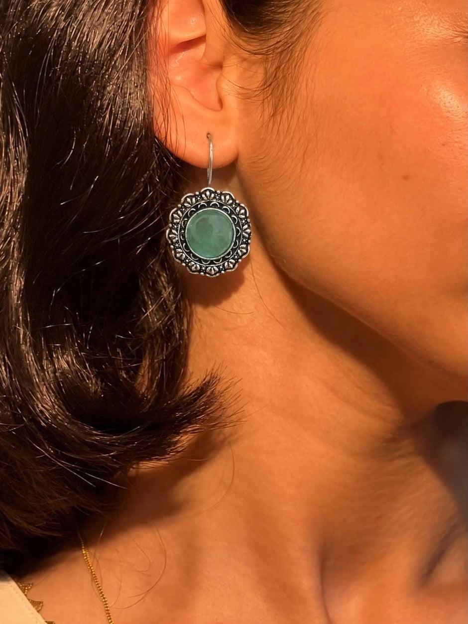 Oxidised silver floral circular earring worn on a woman's ear showing scale and fit
