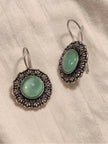Front and side view of oxidised silver circular drop earrings laid on white fabric