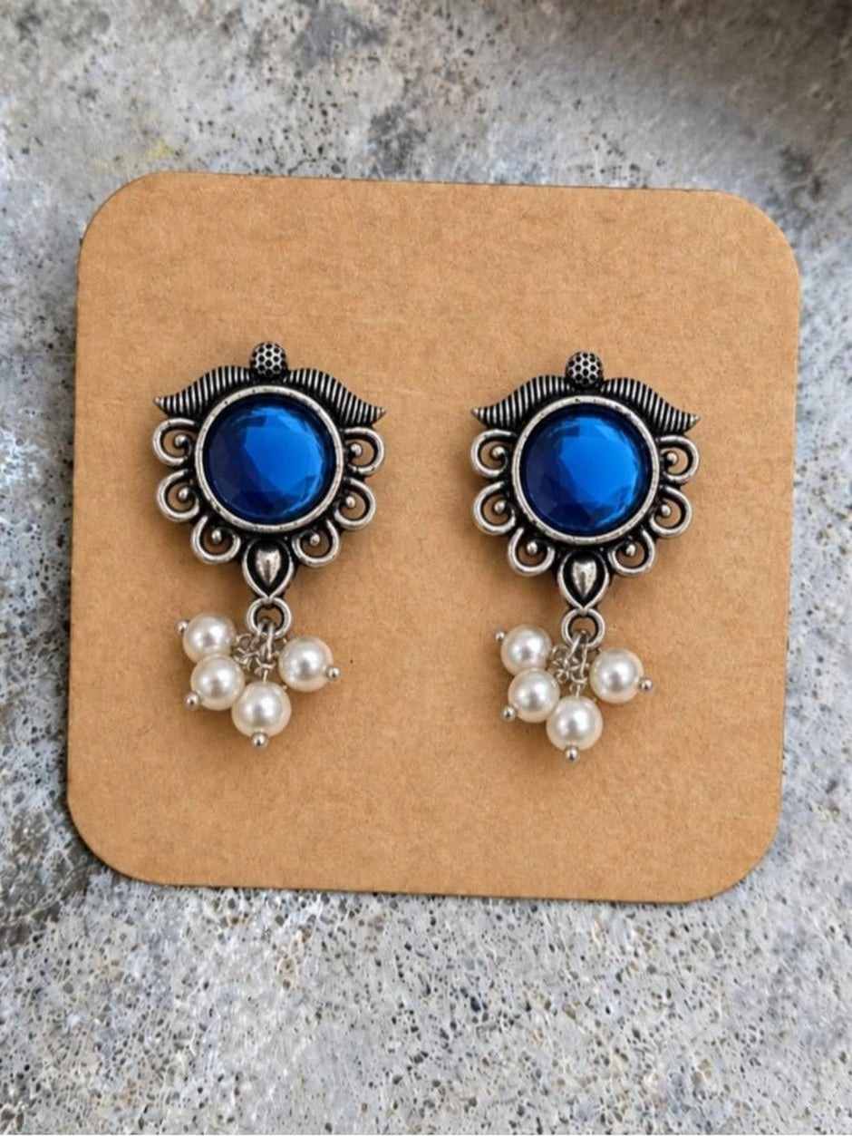 Pair of oxidised silver blue stone pearl drop stud earrings displayed on a kraft earring card