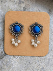 Pair of oxidised silver blue stone pearl drop stud earrings displayed on a kraft earring card