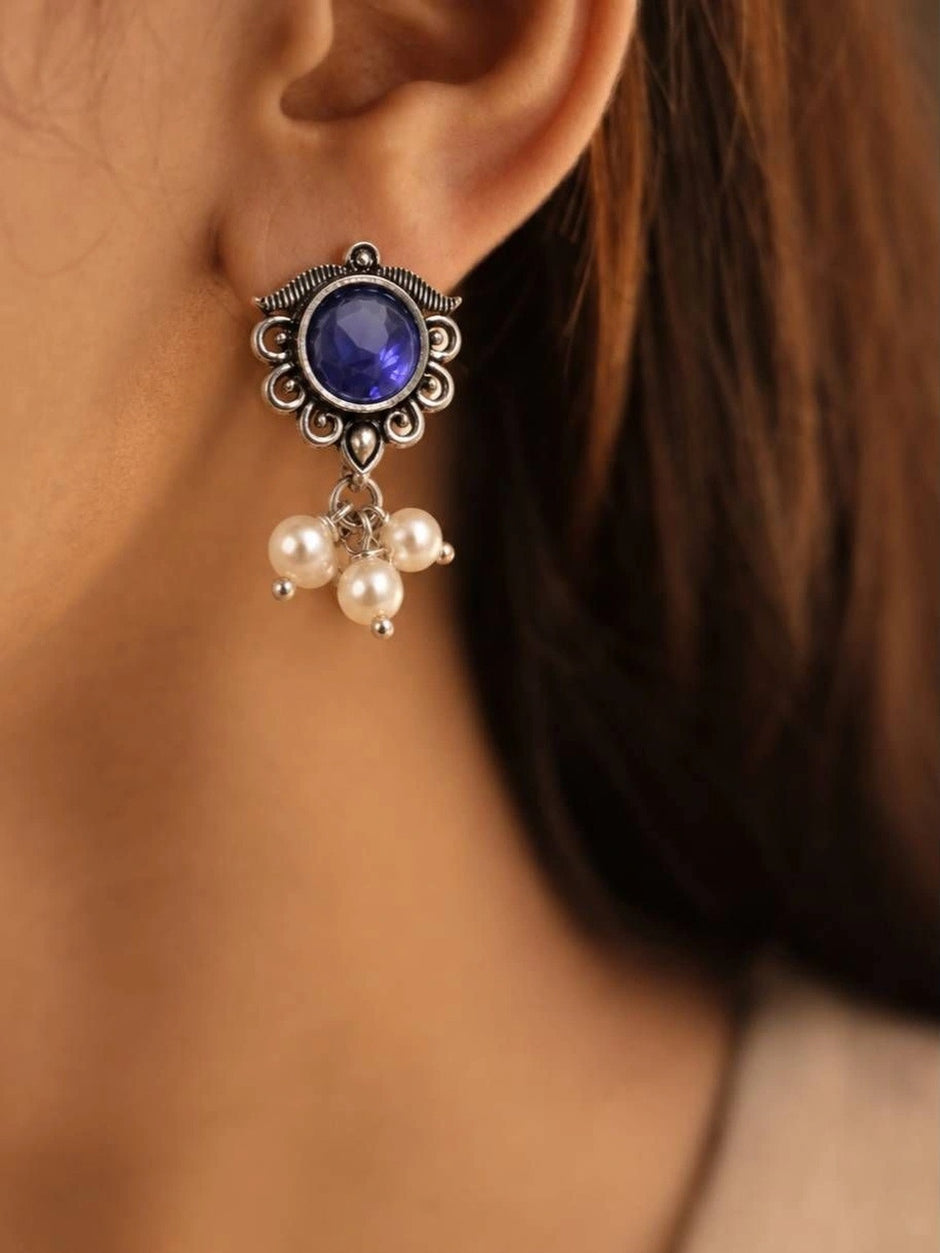Oxidised silver stud earring with blue glass stone and pearl drop cluster worn on a woman's ear