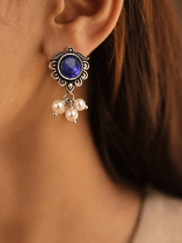 Oxidised silver stud earring with blue glass stone and pearl drop cluster worn on a woman's ear