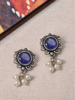 Two oxidised silver blue stone stud earrings with pearl drop clusters laid flat on a linen background