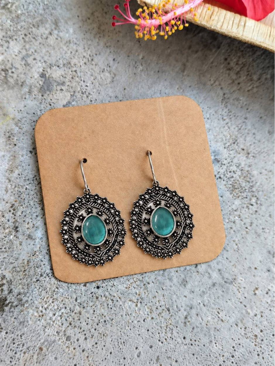 Pair of oxidised silver floral disc earrings with turquoise cabochon stone on brown display card