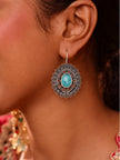 Woman wearing oxidised silver floral disc earring with turquoise stone on fish hook wire