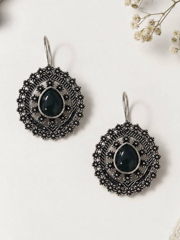 Two oxidised silver mandala disc earrings with black centre stones laid flat on a white surface