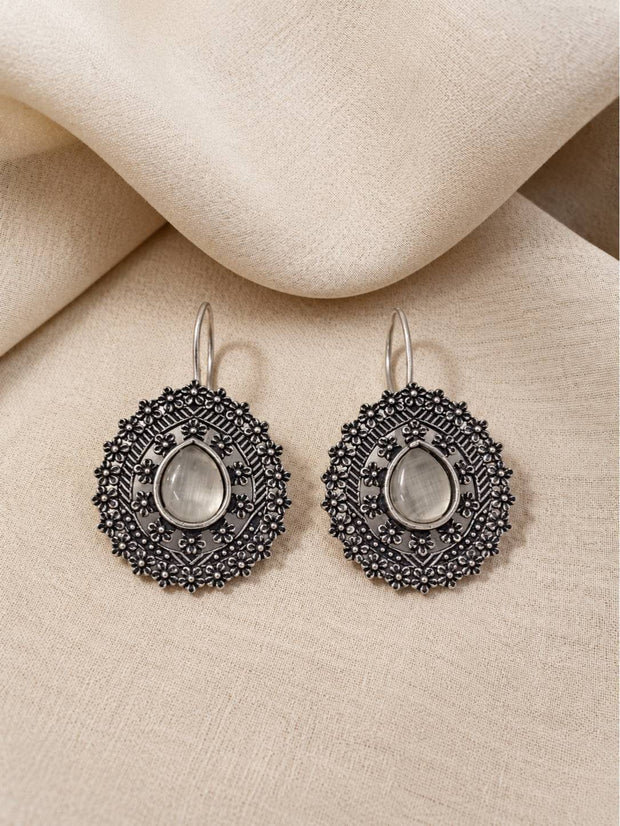 Front view of oxidised silver mandala disc earrings laid flat on cream linen fabric