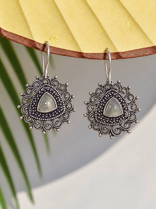 Pair of oxidised silver filigree dangle earrings with moonstone-look cabochon hung from a yellow fan display