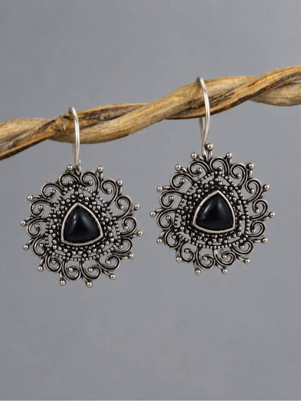 Pair of oxidised silver tribal drop earrings with black triangular stone hanging from a wooden twig