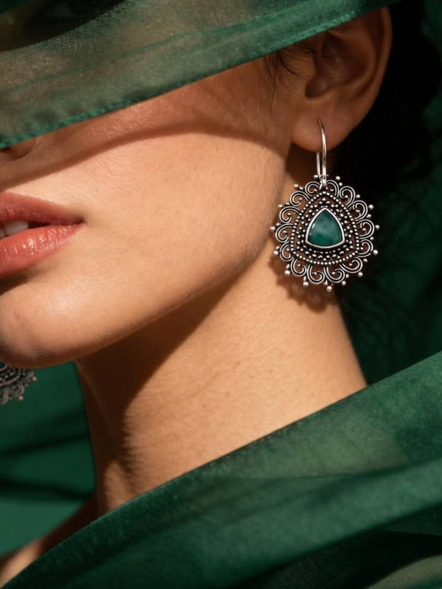 Close-up of oxidised silver filigree earring worn on a woman's ear with a green organza dupatta draped around