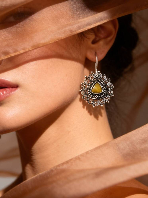 Close-up of oxidised silver filigree drop earring with amber stone worn on a woman's ear