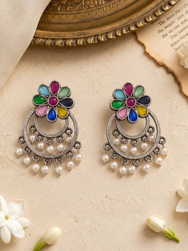 Front view of multicolour flower chandbali earrings with pearl drops placed near a decorative brass tray and white jasmine flowers