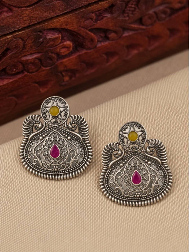 Front view of both oxidised silver filigree earrings laid flat on a beige surface beside a carved wooden box