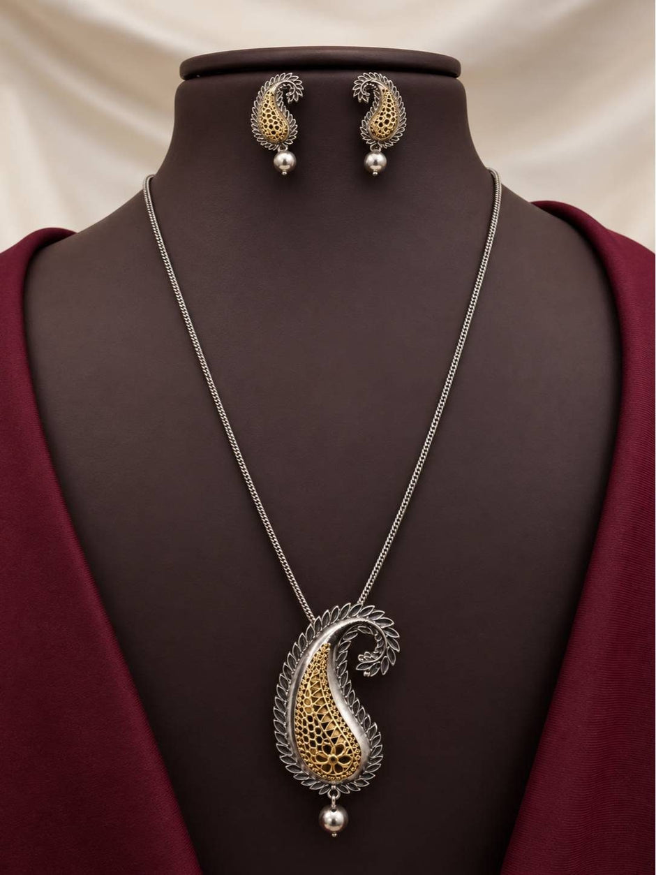 Dual-tone oxidised paisley pendant necklace and matching stud earrings displayed on a dark burgundy mannequin bust