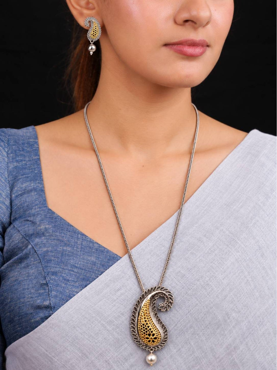 Woman wearing oxidised paisley pendant necklace and matching earrings over a grey and blue saree