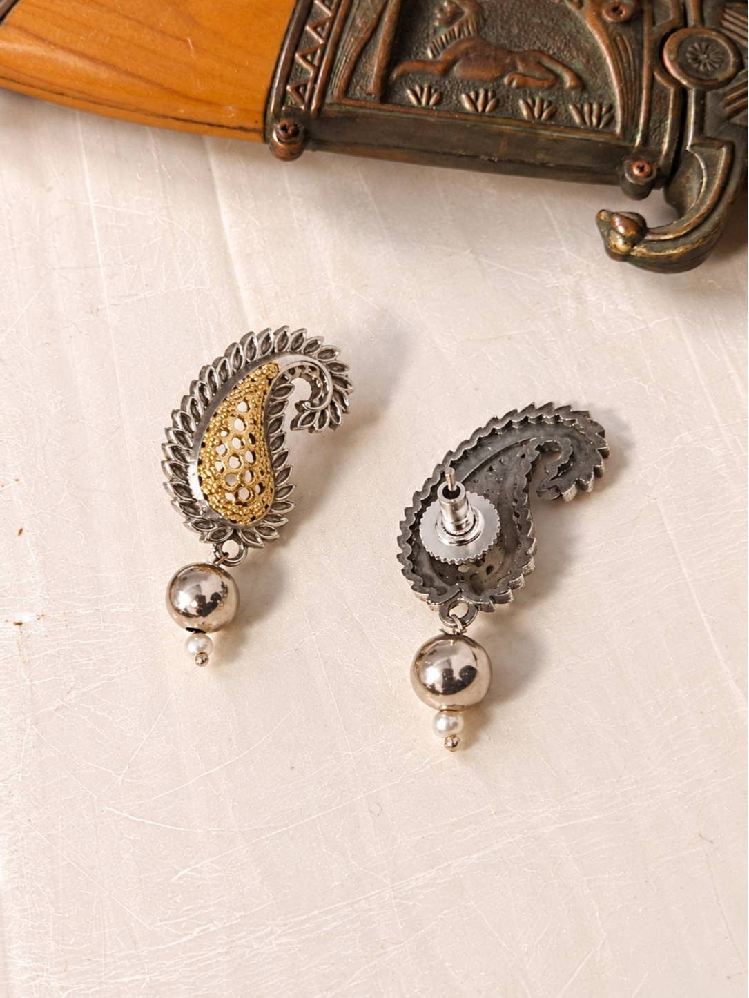 Front and back view of oxidised dual-tone paisley stud earrings showing gold filigree detail and push-back fastening