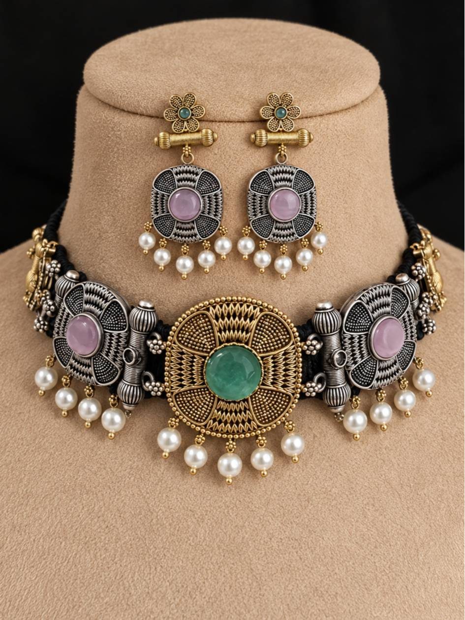 Oxidised dual-tone choker set with green stone centrepiece and pearl drops displayed on a beige jewellery bust