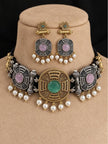 Oxidised dual-tone choker set with green stone centrepiece and pearl drops displayed on a beige jewellery bust