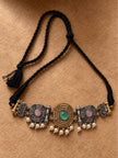 Flat lay of oxidised choker necklace on braided black dori with tassel closure on a tan background