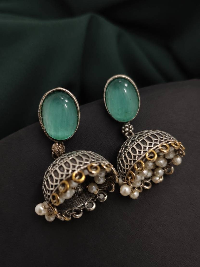 Close-up of oxidised silver jhumka earrings with seafoam green cabochon top and white pearl fringe drops