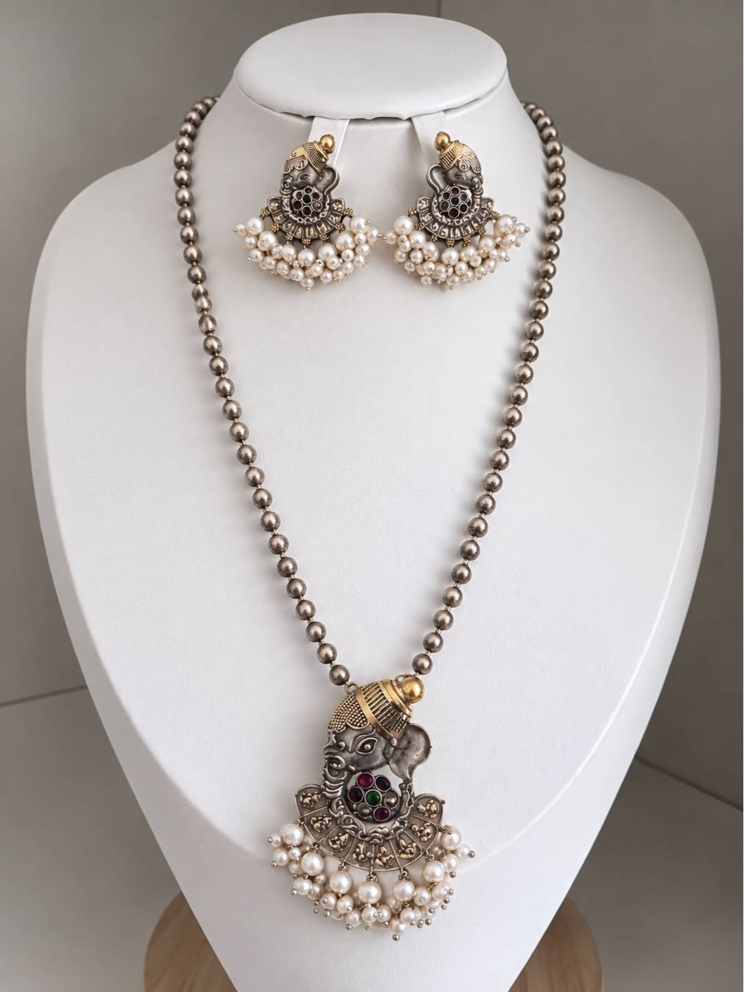 Oxidised dual-tone Ganesha long necklace set displayed on a white jewellery bust with matching pearl-drop earrings