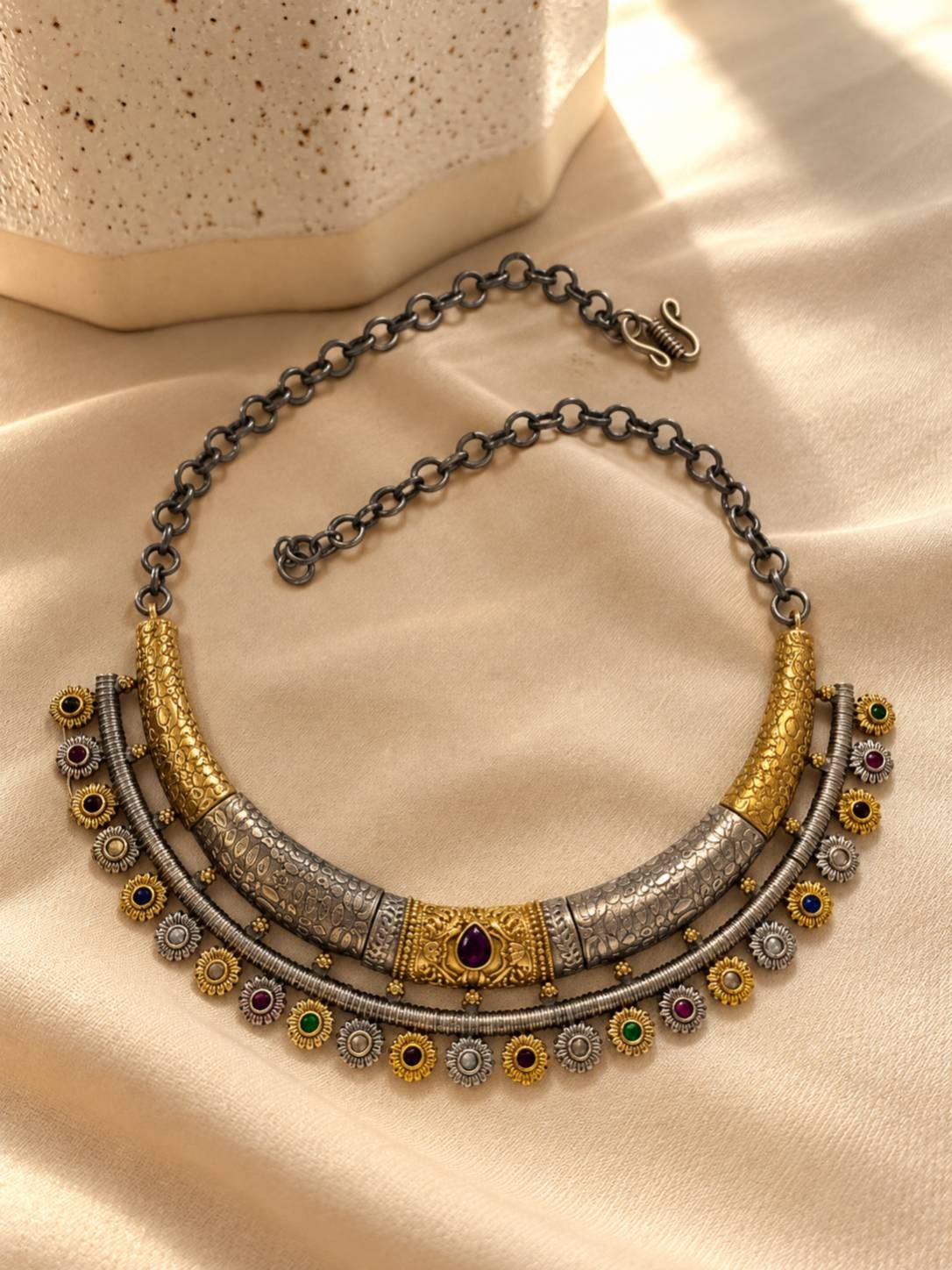 Flat lay of oxidised dual-tone layered choker necklace with multicolour stone floral motifs on cream fabric