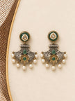 Close-up flat lay of matching dual-tone chandbali earrings with green stones and pearl drops