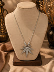 Oxidised silver leaf pendant necklace displayed on a beige jewellery bust with decorative brass props in background