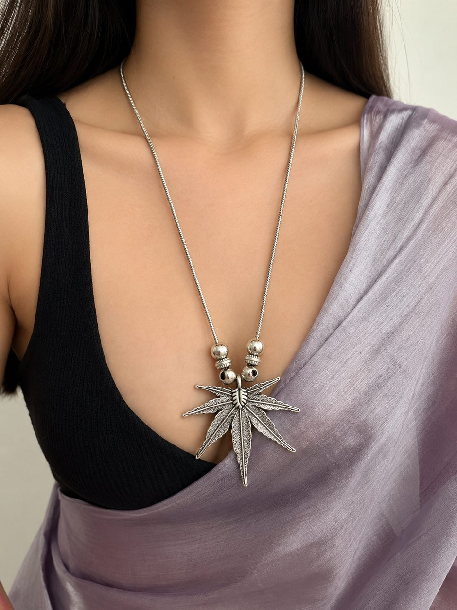 Model wearing oxidised silver leaf pendant long necklace over black blouse with lavender saree draped over shoulder