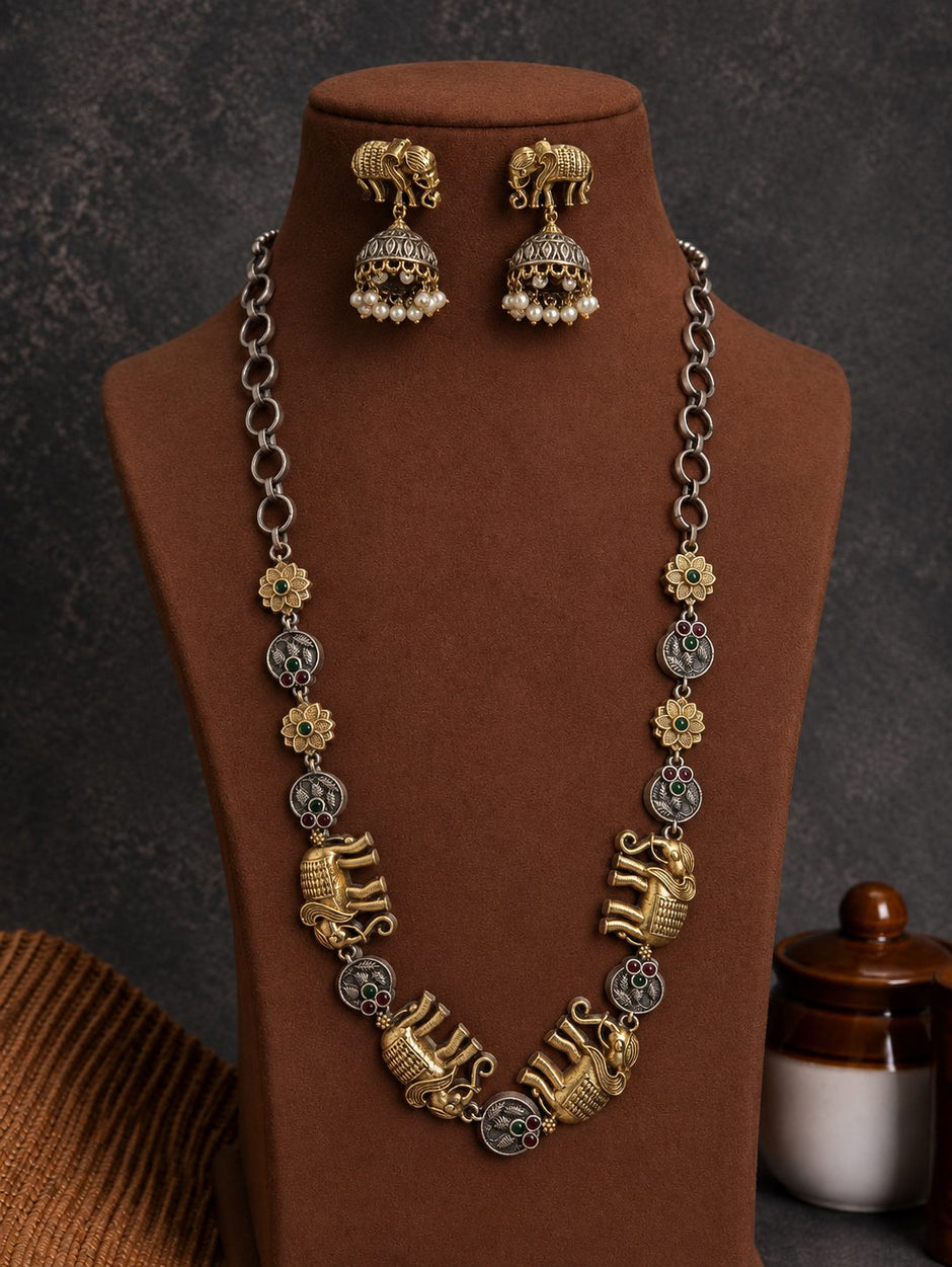 Oxidised gold elephant necklace set with jhumka earrings displayed on a brown velvet bust