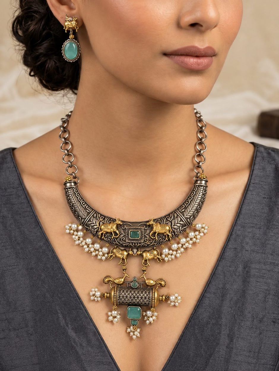 Model wearing oxidised silver choker necklace and matching Nandi bull drop earrings with a grey ethnic top