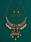 Oxidised dual tone hasli necklace set with pearl clusters and green red stones laid flat on teal velvet