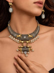 Model wearing oxidised temple necklace set with cow motif earrings against dark skin-tone close-up
