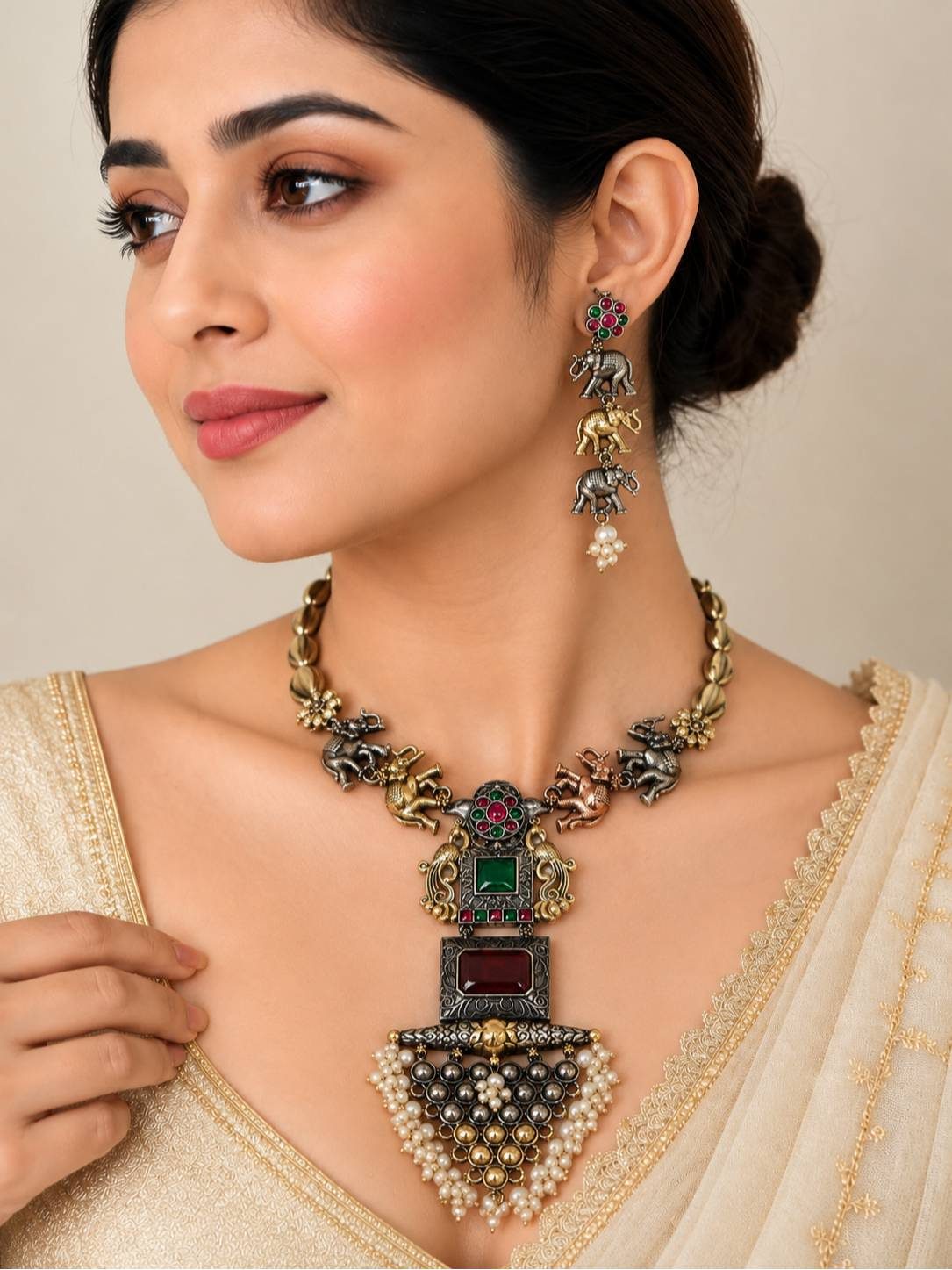 Woman wearing oxidised elephant necklace with matching triple elephant drop earrings styled with a cream embroidered saree
