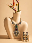 Oxidised elephant necklace displayed on a beige bust mannequin with matching earrings placed beside a bird-of-paradise flower vase