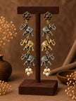 Close-up of triple cascading elephant drop earrings with red and green stone tops and pearl cluster finish on a brown velvet stand
