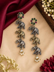 Close-up of triple elephant drop earrings with multicolour floral tops and pearl clusters on cream surface