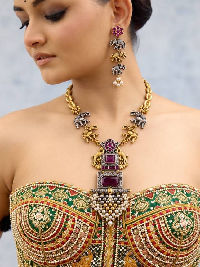 Model wearing oxidised dual-tone elephant necklace and earrings set styled over an embroidered green and gold bridal lehenga blouse