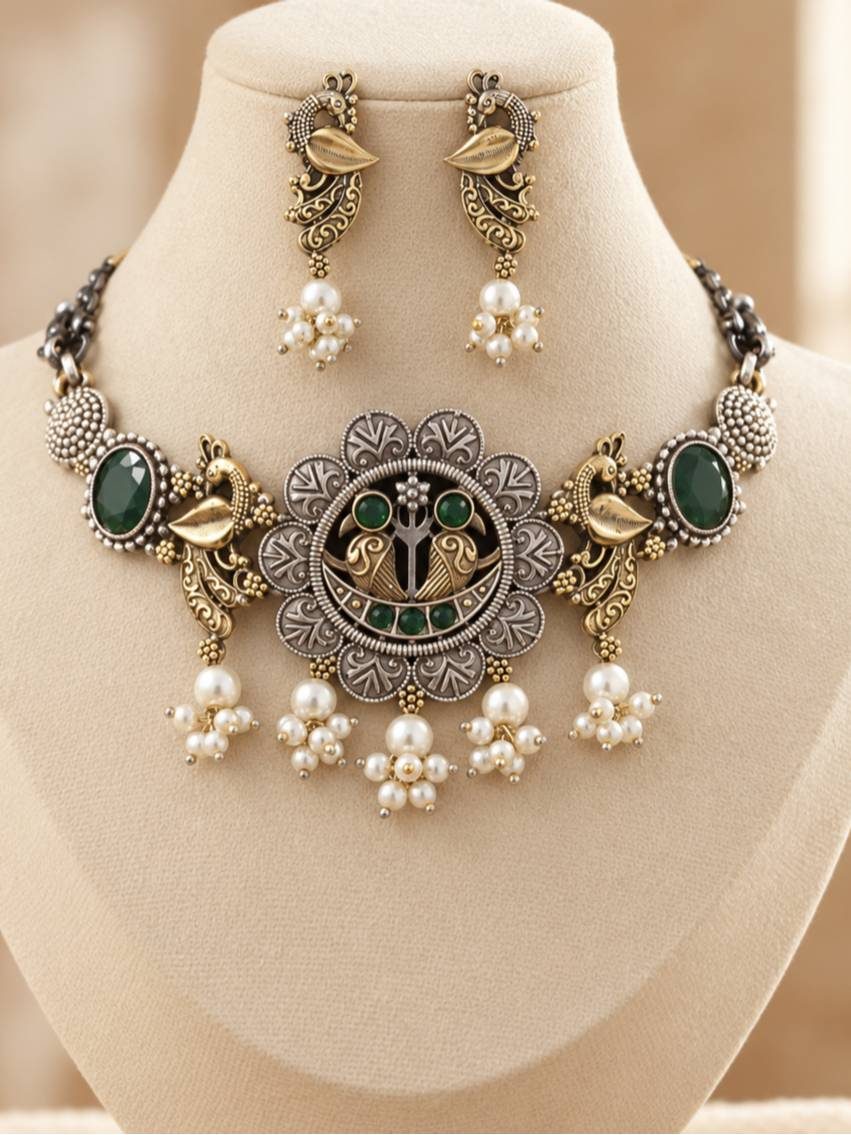 Oxidised dual-tone peacock choker necklace and earring set displayed on a cream jewellery bust