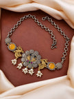 Flat lay of oxidised peacock choker with yellow stones and pearl drops on cream fabric