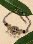 Oxidised peacock choker necklace with pearl drops laid flat on mango leaves and sandy surface