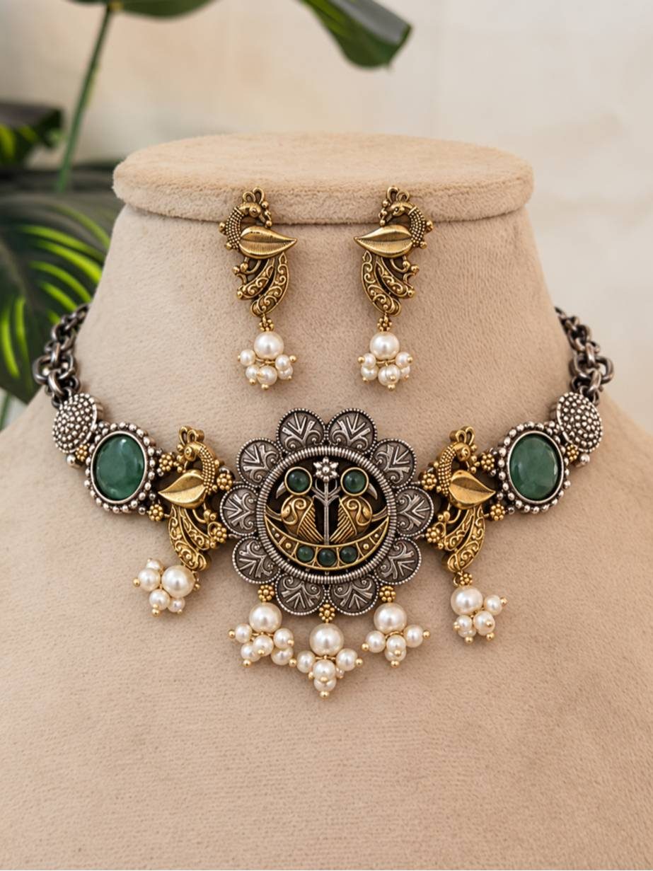 Oxidised dual-tone peacock choker necklace and earring set displayed on a beige jewellery bust