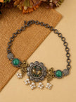 Flat lay of oxidised peacock choker necklace with green cabochons and pearl drops on burlap fabric