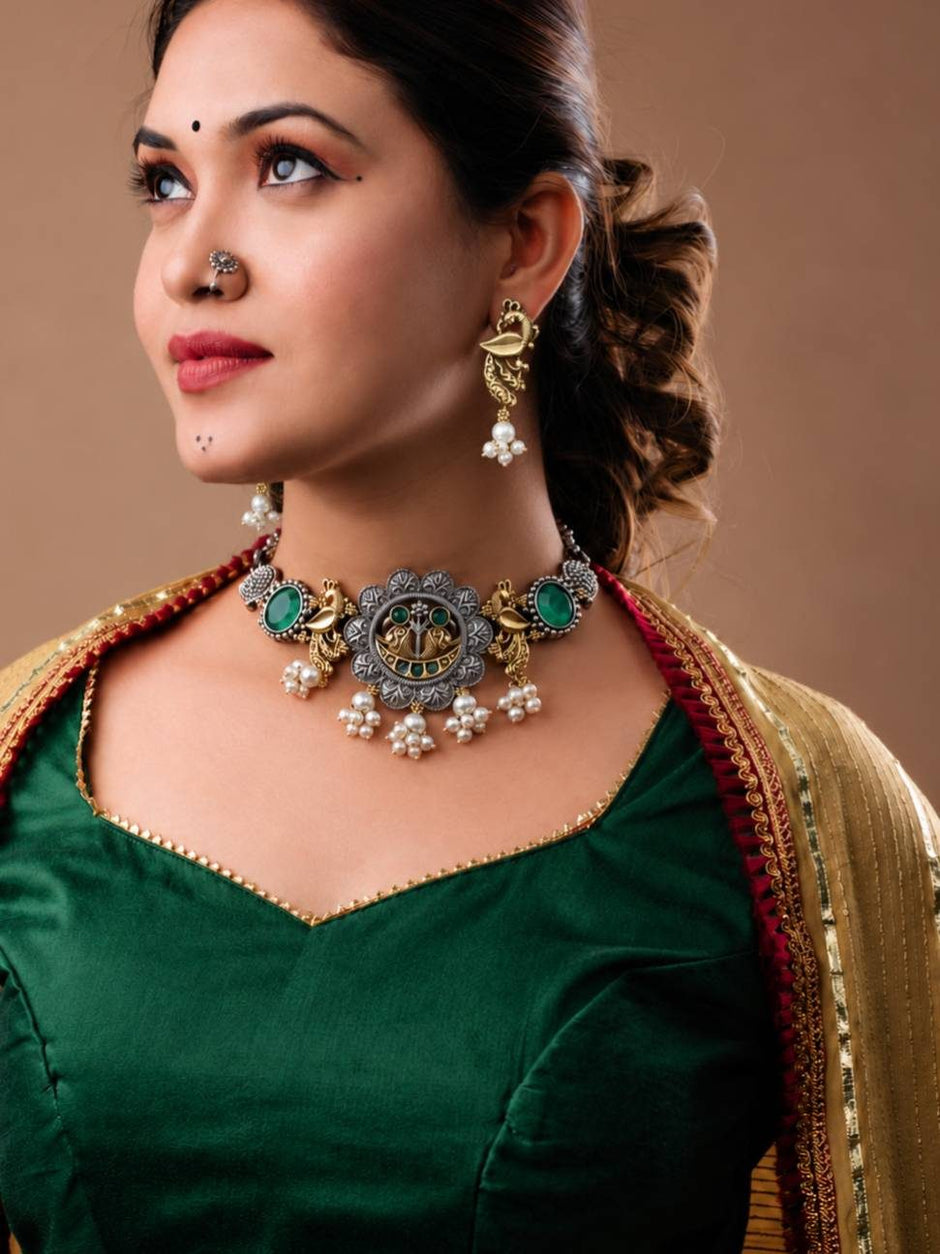Woman wearing oxidised peacock choker set with green cabochon stones paired with a dark green silk blouse