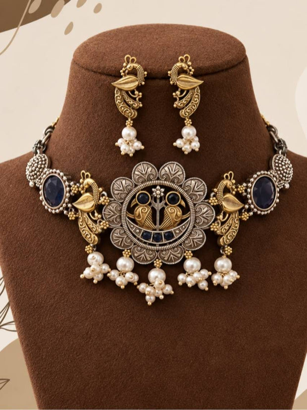 Oxidised dual-tone peacock choker necklace and stud earring set displayed on a brown jewellery bust